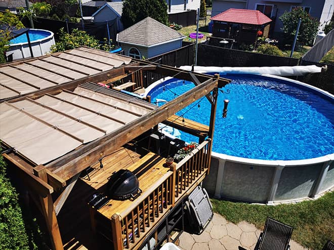 Toile sur-mesure servant de toit ouvrant sur un balcon de maison adjacent une piscine hors-terre